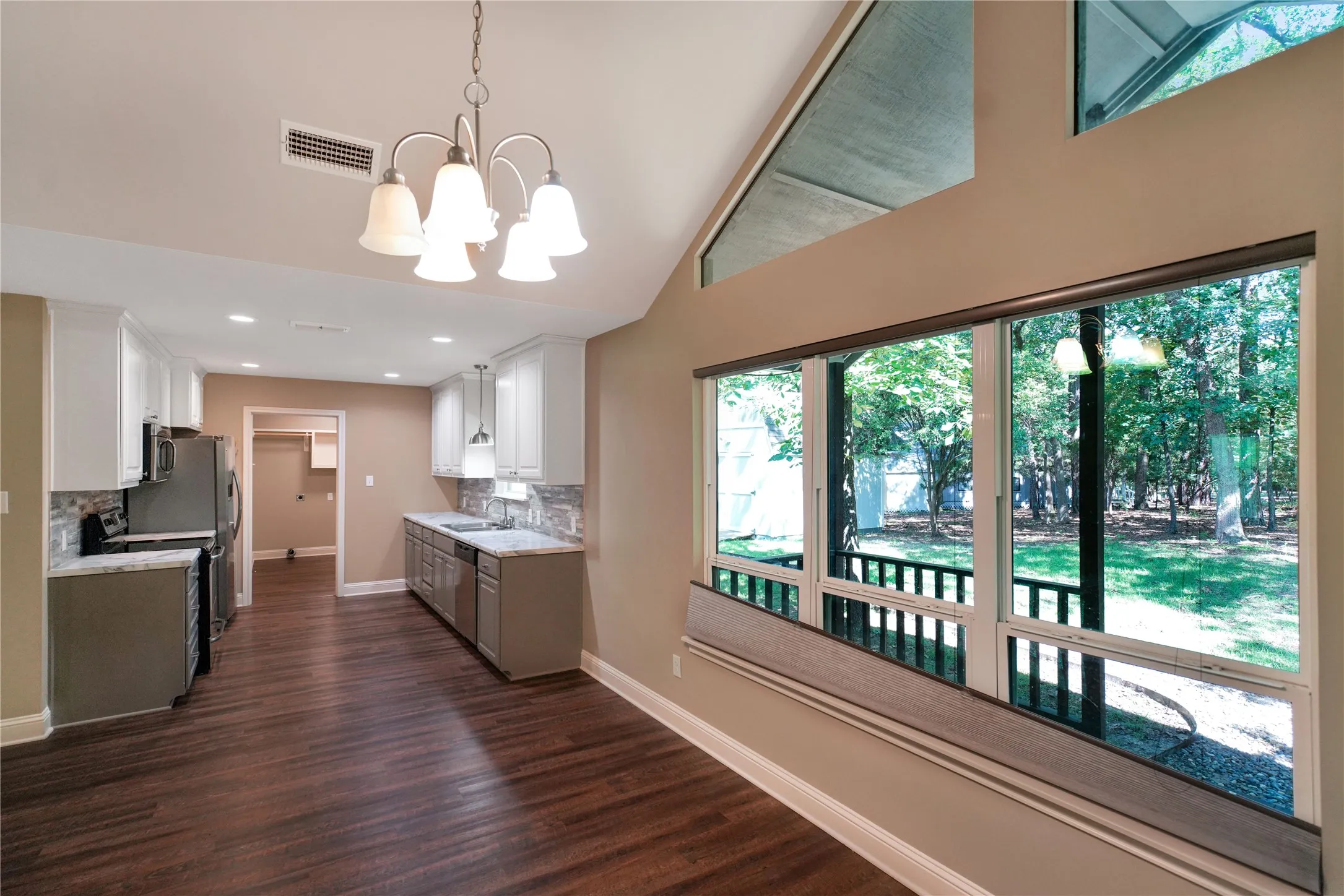 Vaulted ceilings featuring upper transom windows and a multi-pane lower window overlooking the outdoor​​‌​​​​‌​​‌‌​‌‌​​​‌‌​‌​‌​‌​​​‌​​ area