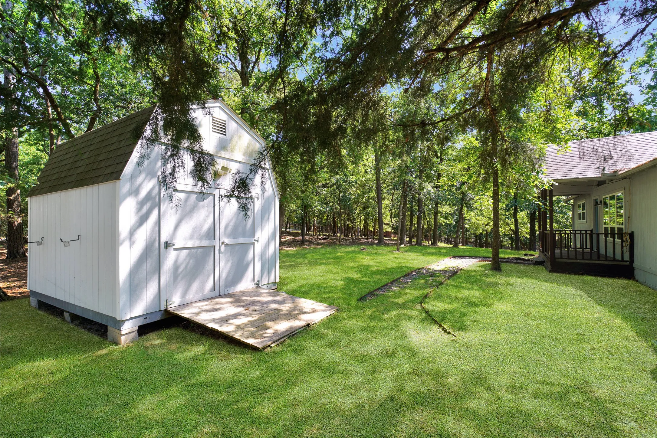 Gambrel-roof shed with white vertical siding and dual access doors