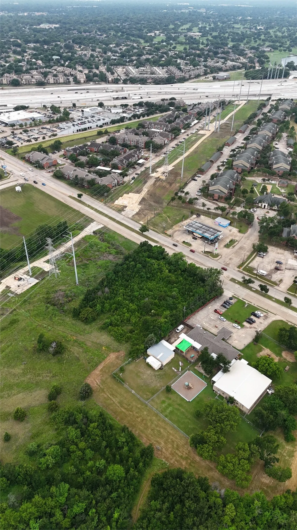 Expansive aerial view showcasing a significant parcel of undeveloped land surrounded by established residential properties and roadways