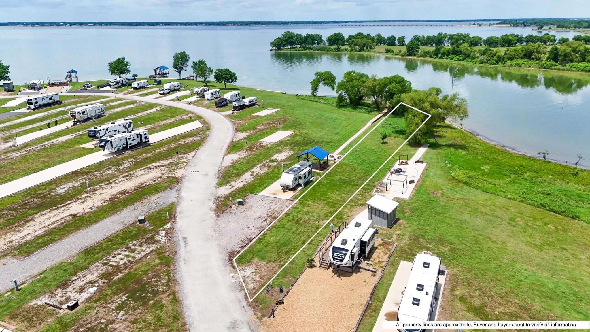 Expansive lakefront property featuring a designated RV pad with gravel surfacing, a private covered picnic area, and direct water access