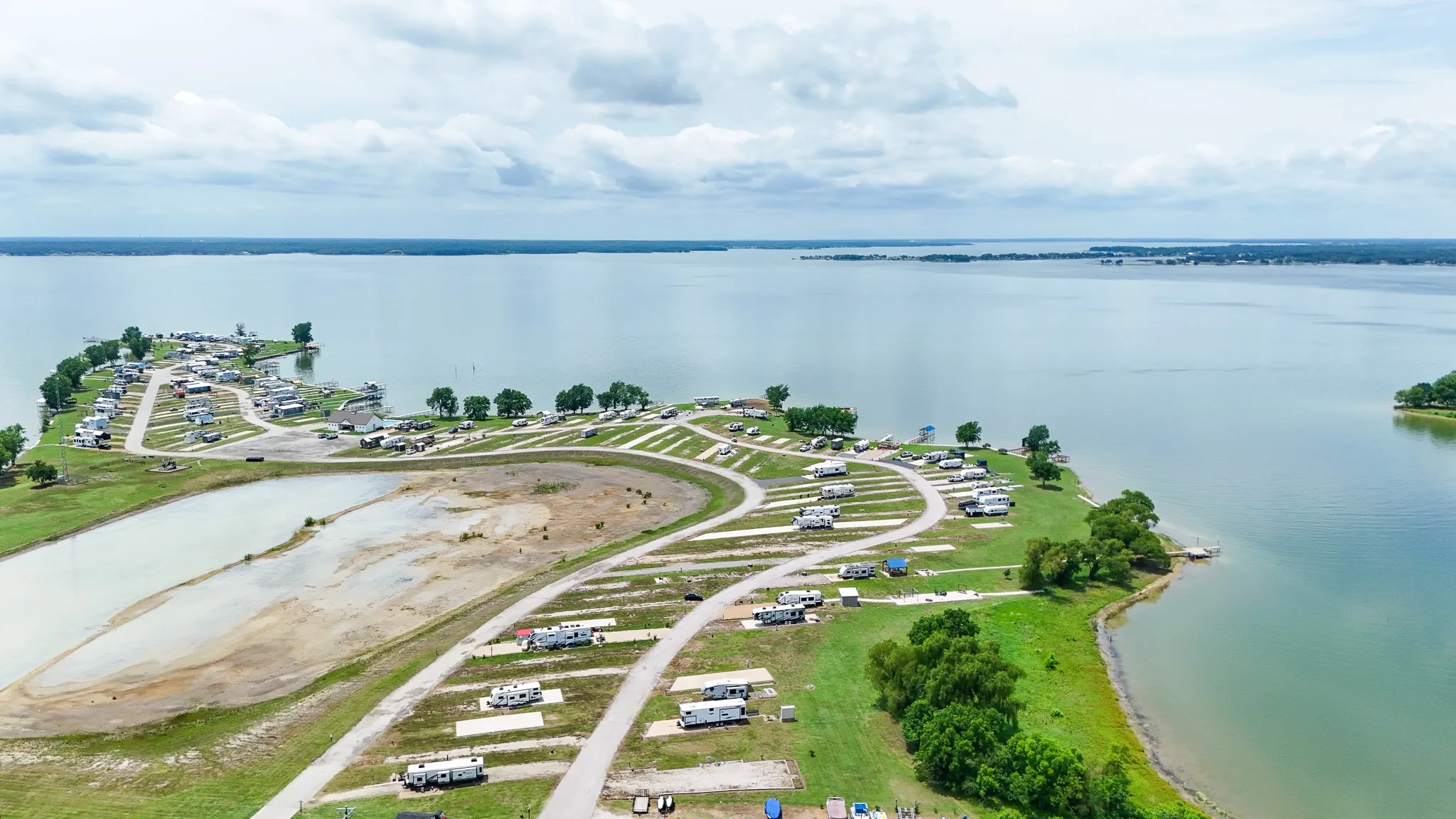 Expansive waterfront property featuring multiple RV sites with paved access roads and a large central body of water