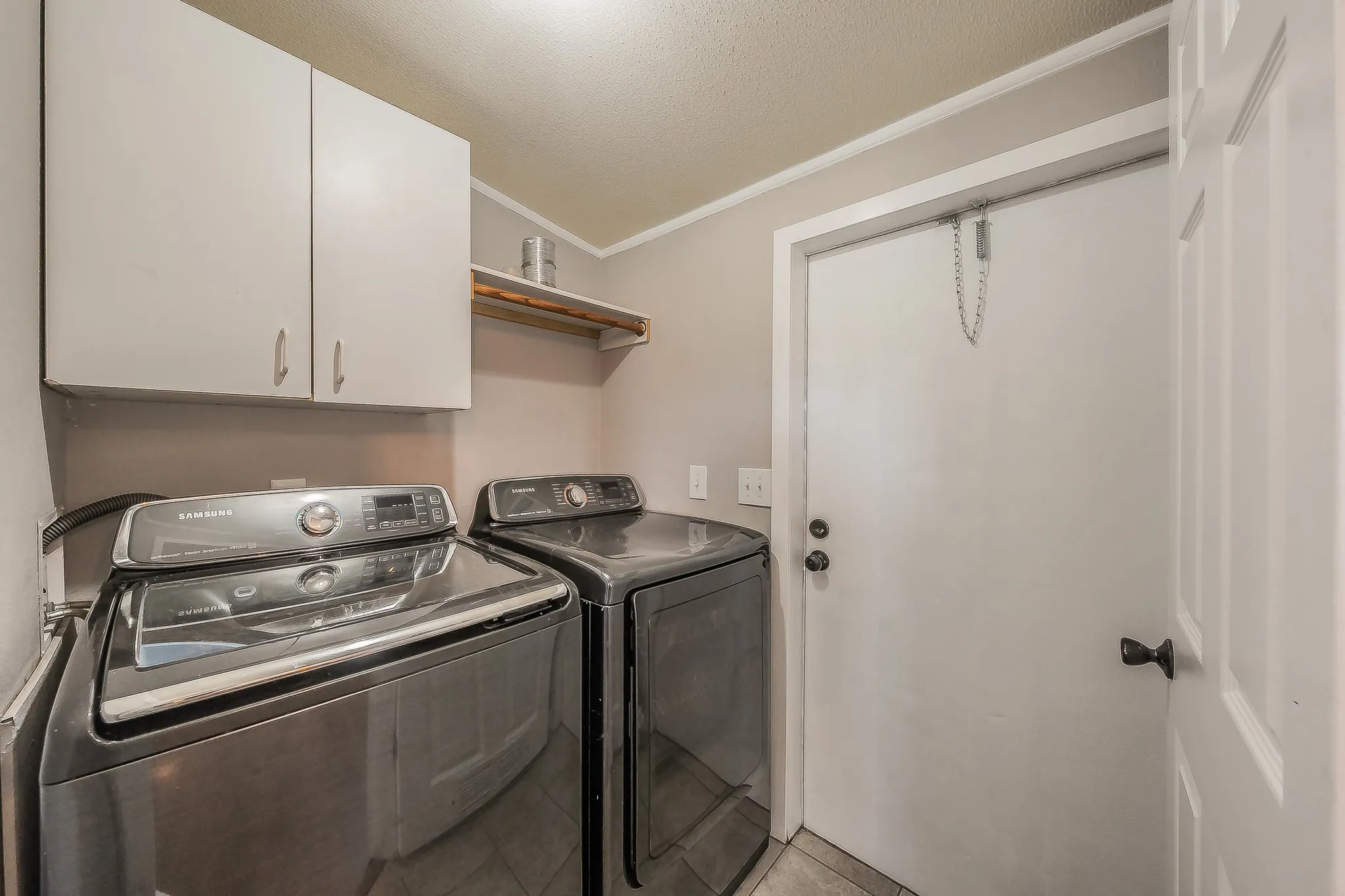  Dedicated laundry room with washer and dryer connections, upper storage cabinets, and exterior access. Washer and dryer excluded.