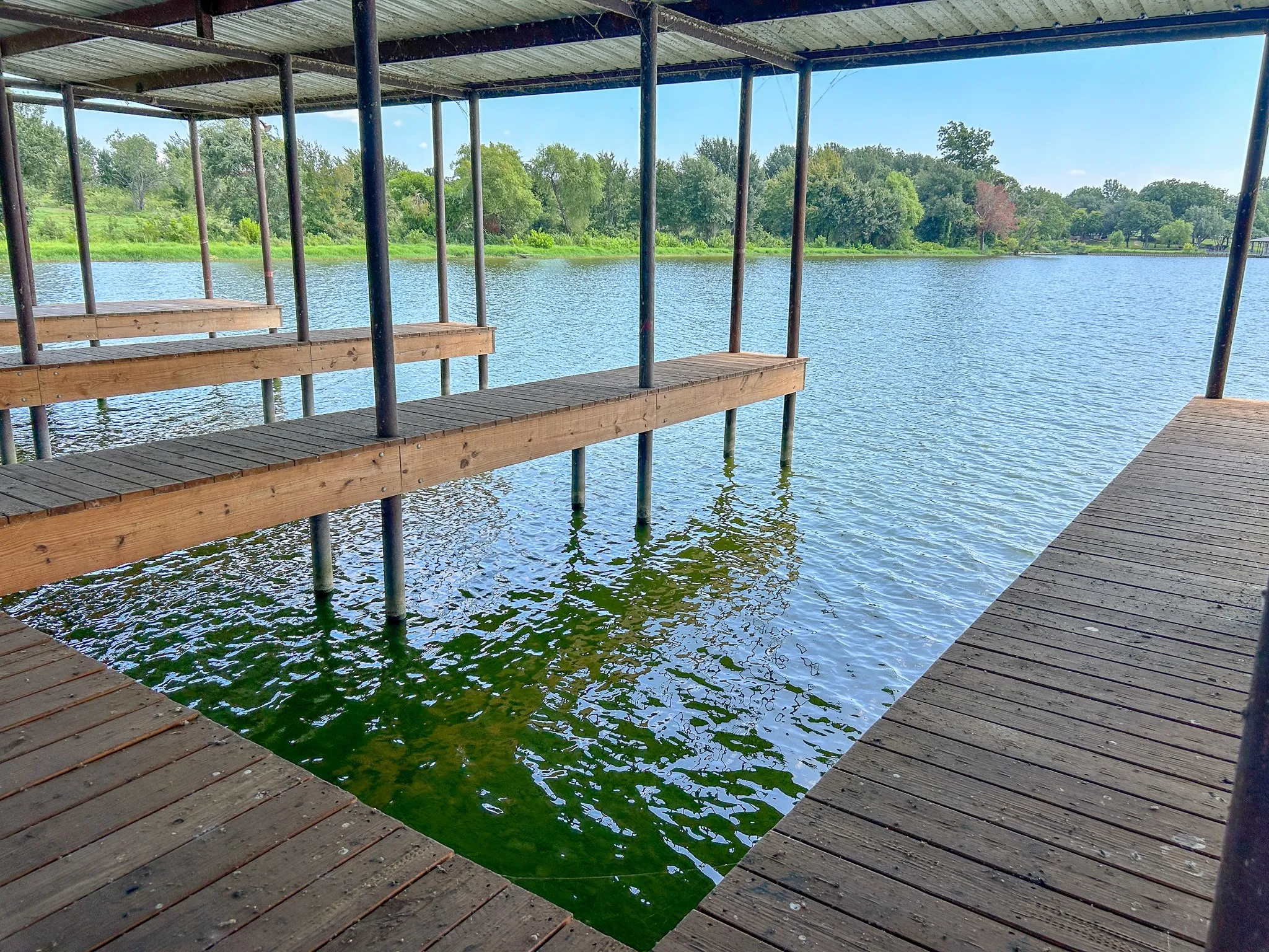 Covered boat dock featuring multiple slips with wood plank decking, supported by metal pilings