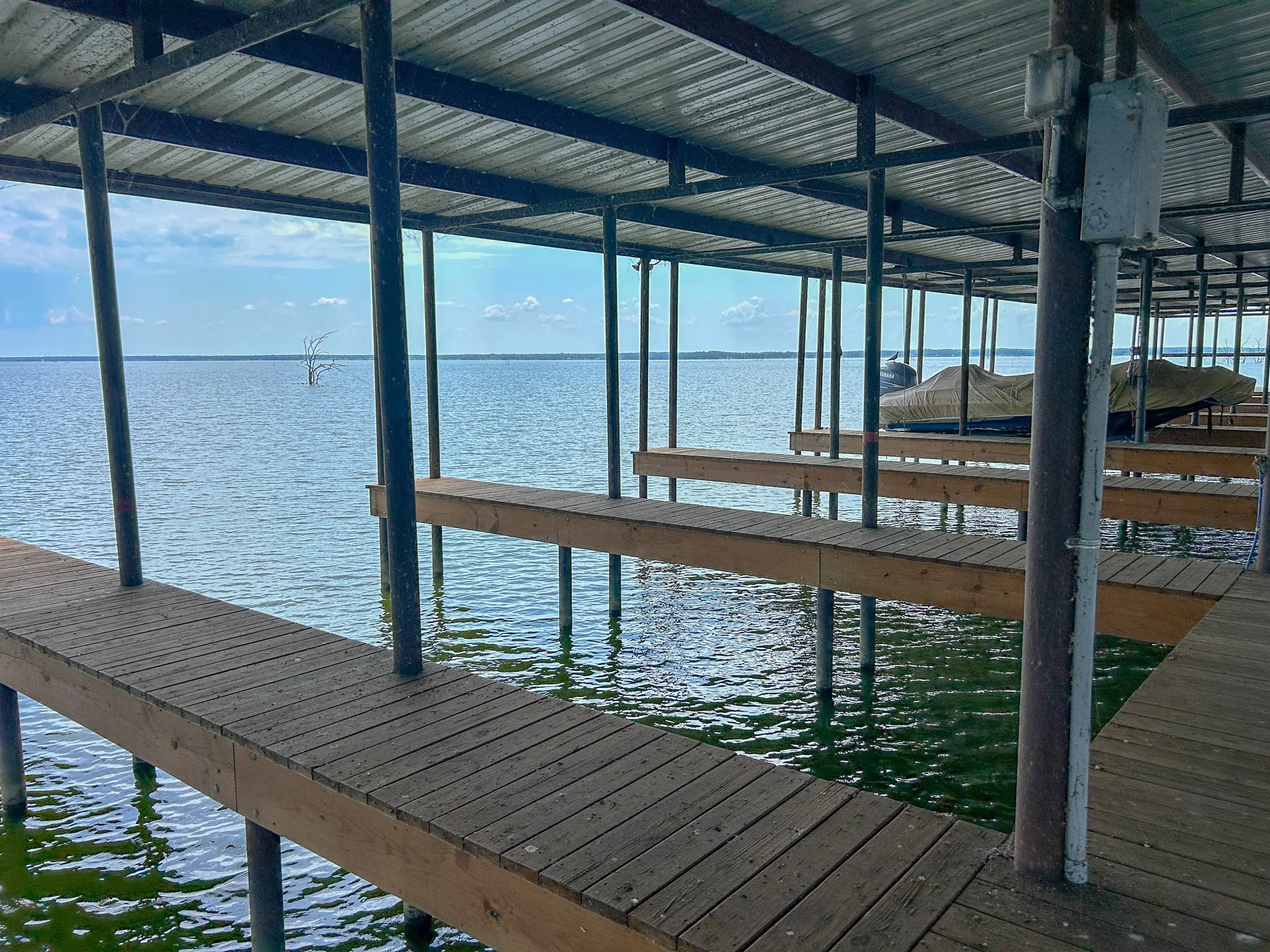 Covered boat dock featuring multiple slips, wood decking, and galvanized metal roofing