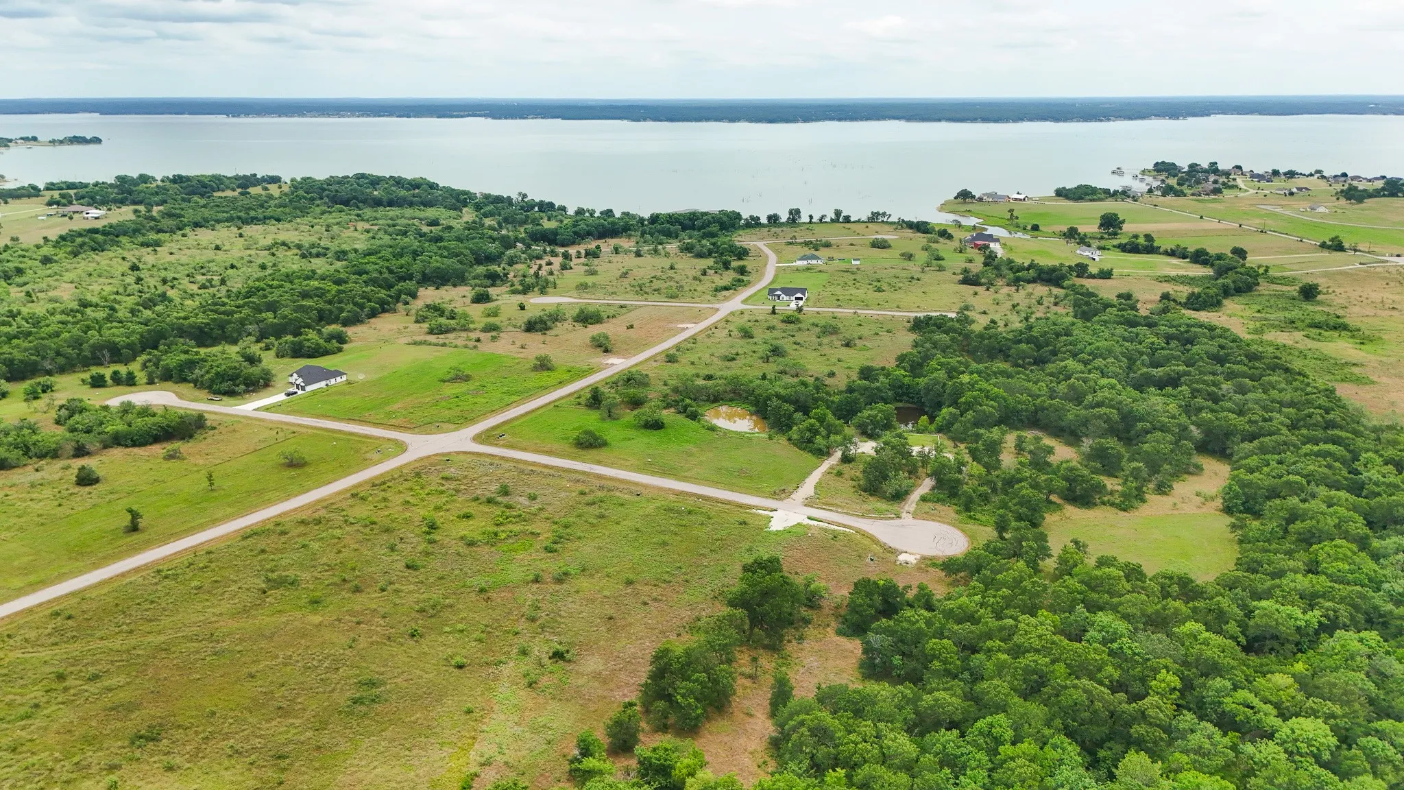 Expansive parcel featuring a tranquil waterfront, established roads, scattered residences, and mature tree coverage