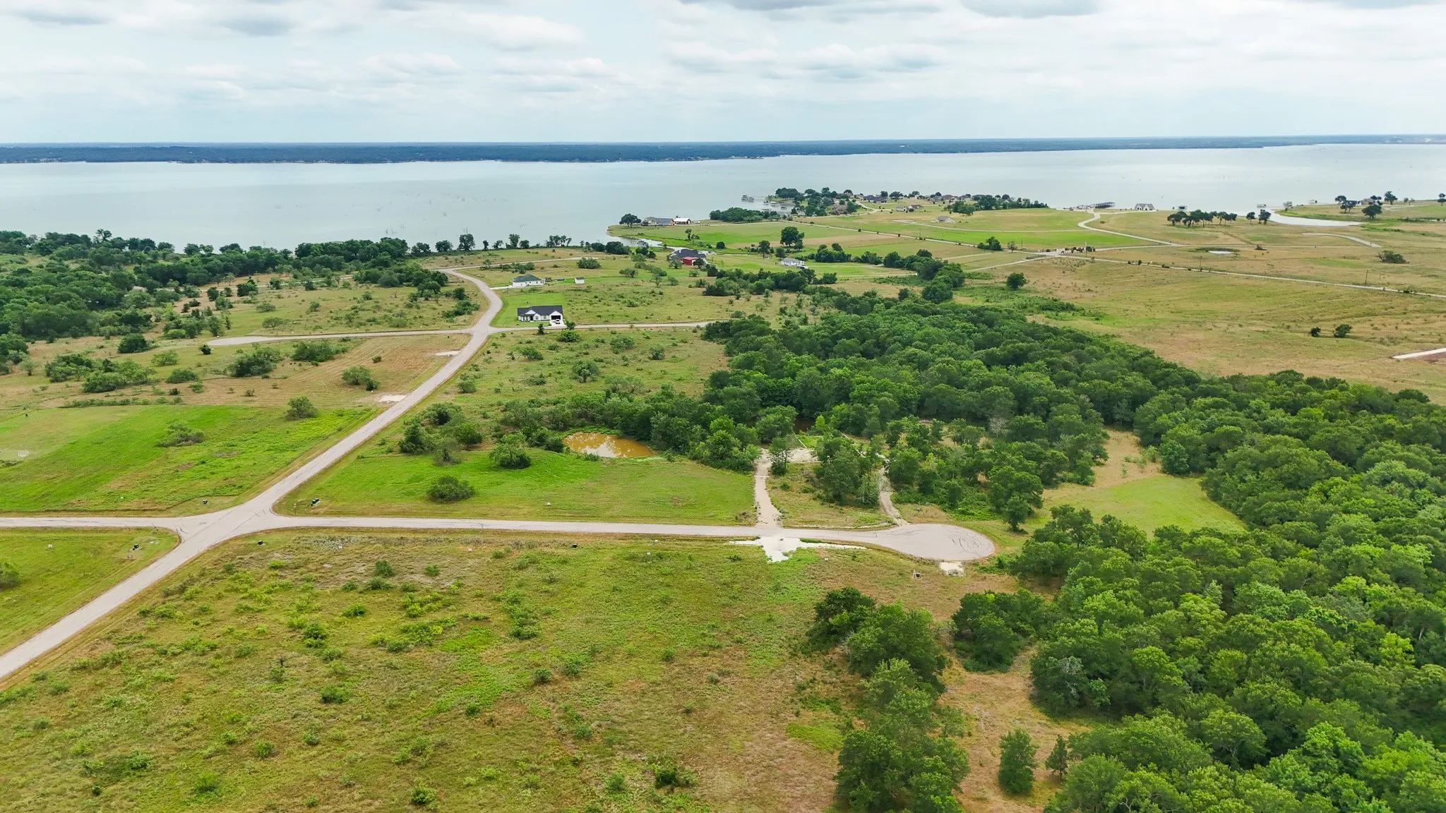 Expansive undeveloped land featuring a substantial body of water, lush green areas, and mature trees