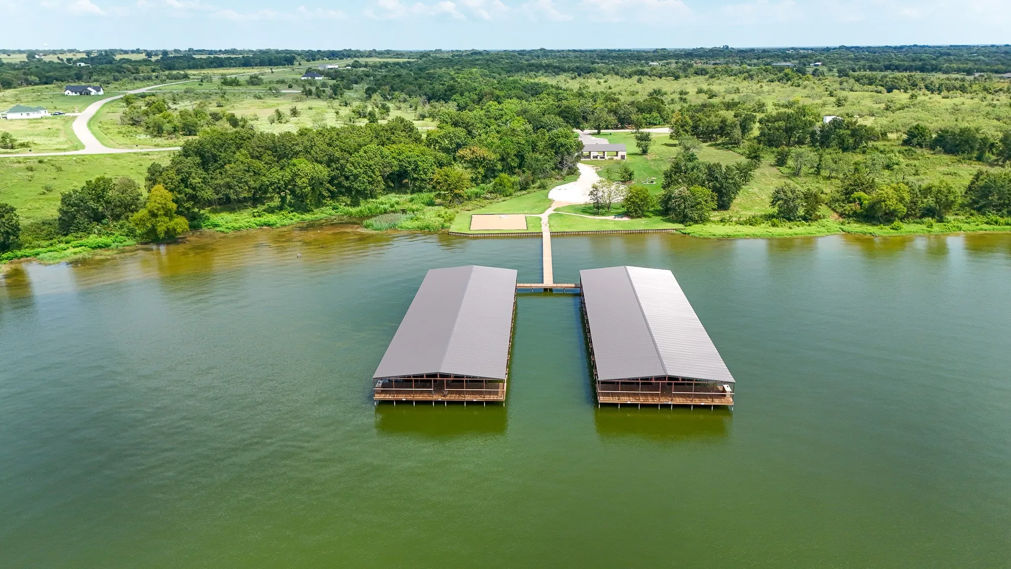 Two covered boat docks featuring metal roofs and wooden structures are situated on the water