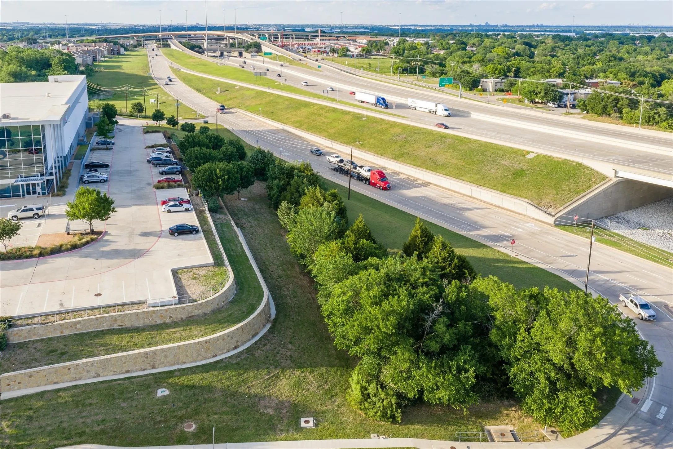 Contemporary commercial building with extensive parking, a tiered retaining wall, and verdant landscaping
