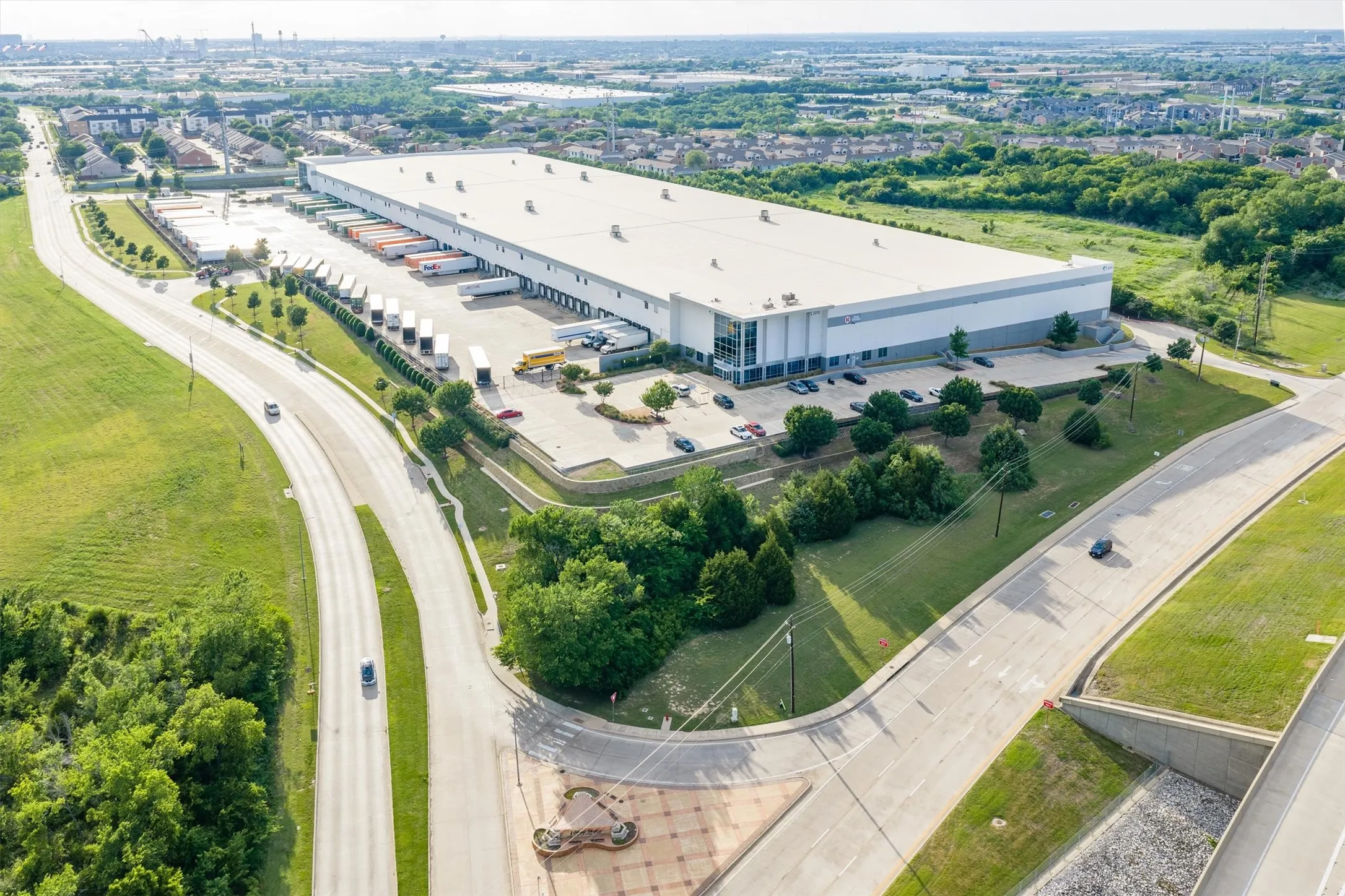 Expansive industrial building featuring multiple loading docks, extensive paved parking, and a large, flat roof