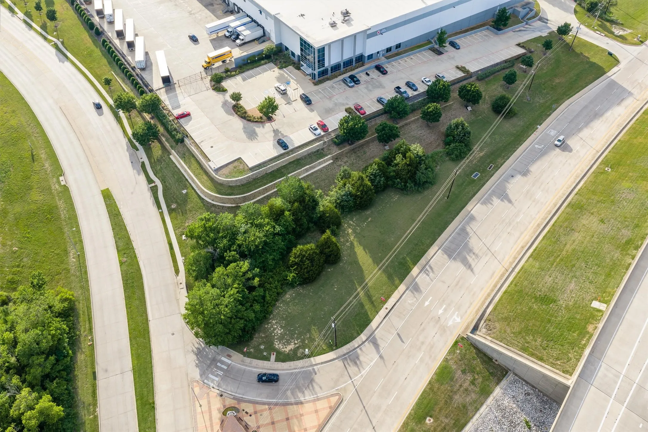 Industrial building featuring multiple dock doors, a large paved parking area, and extensive surrounding green space