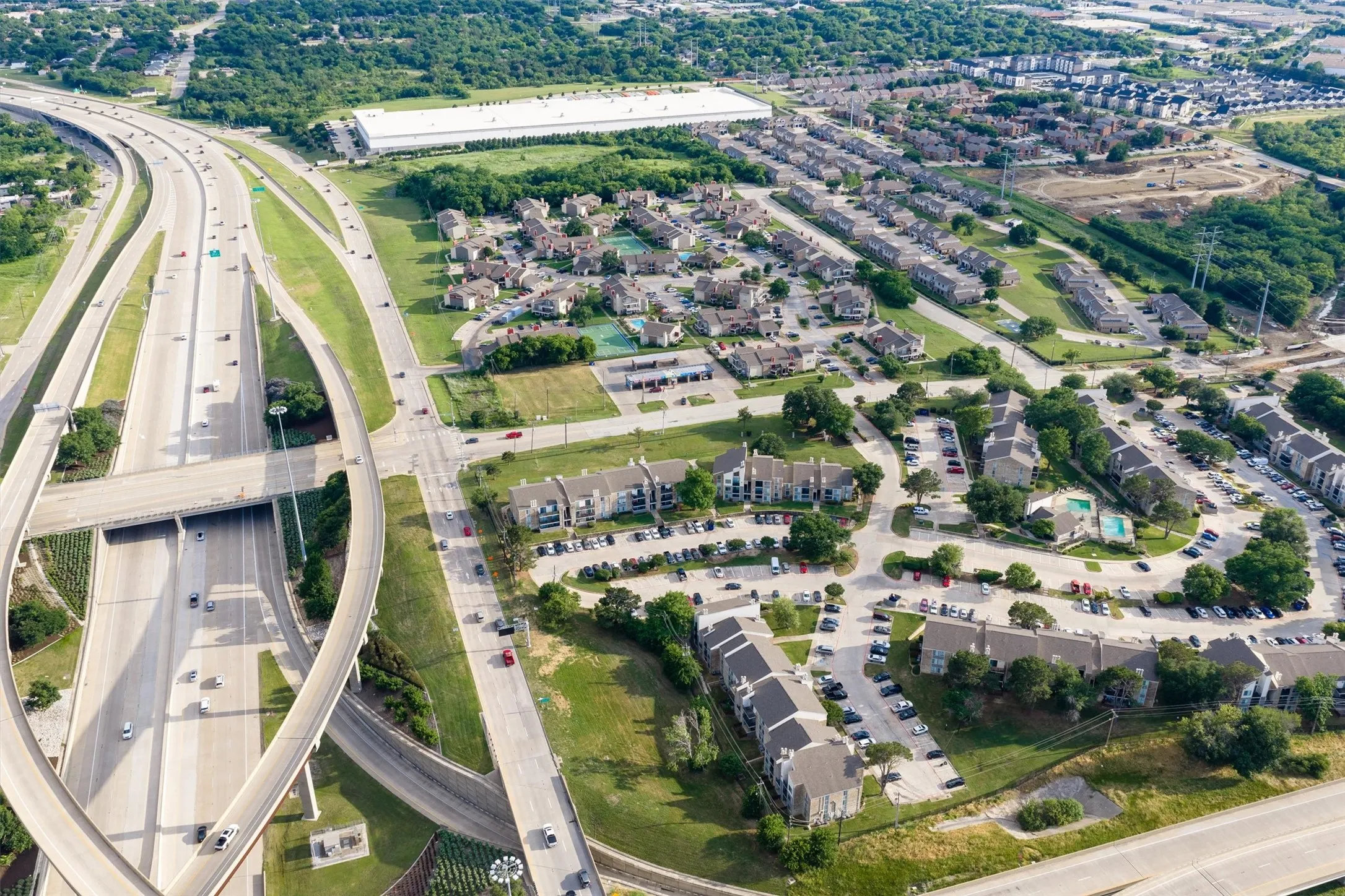 Expansive aerial capture showcasing a multi-lane highway interchange bordering a residential community