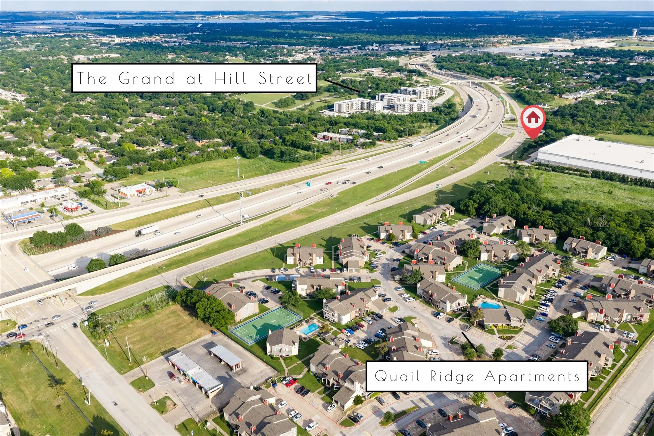 Aerial perspective showcasing a complex of multi-unit residential buildings with numerous parking spaces and green landscaping