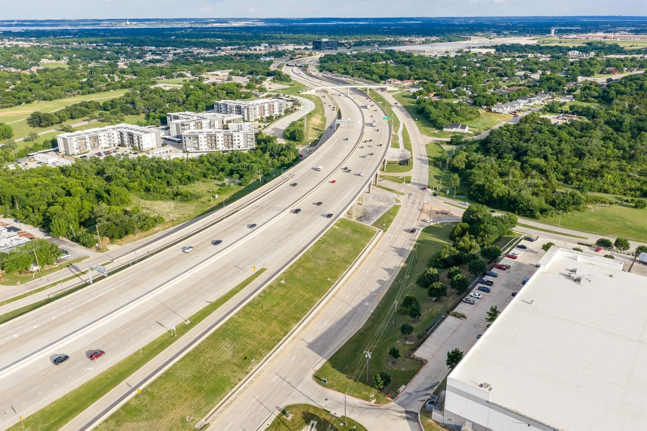 Aerial perspective showcasing a multi-lane highway, surrounding green spaces, and commercial structures