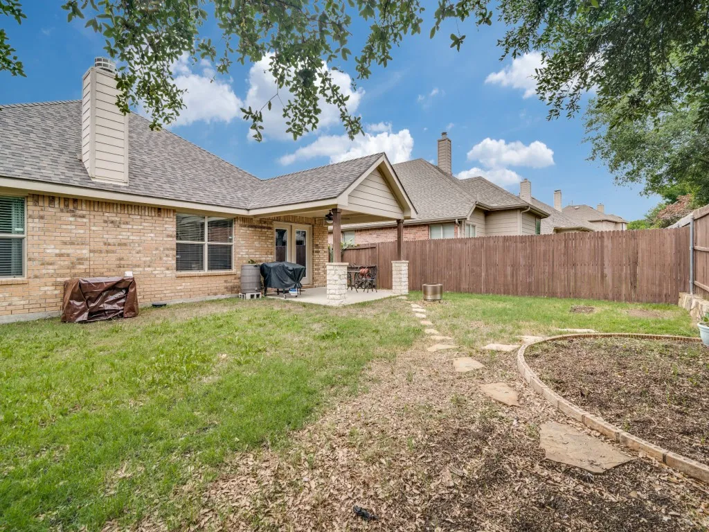 Rear exterior featuring a covered patio, brick facade, and a fenced yard