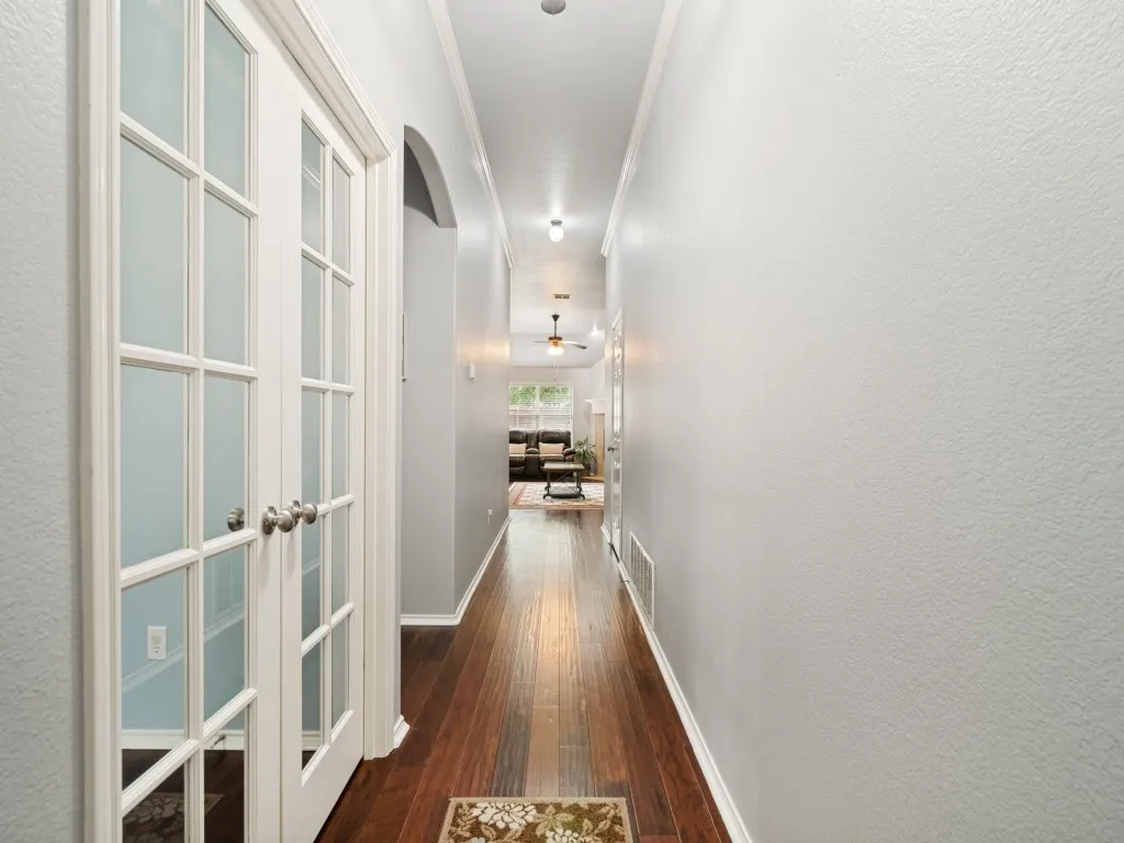 Hallway featuring wood-finish flooring, white trim, recessed lighting, and an arched entry