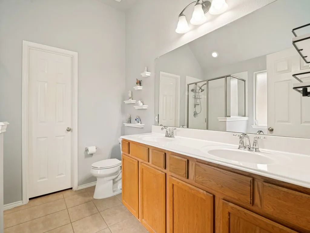 Bathroom featuring a dual vanity with oak cabinetry, an integrated white countertop, and chrome faucets