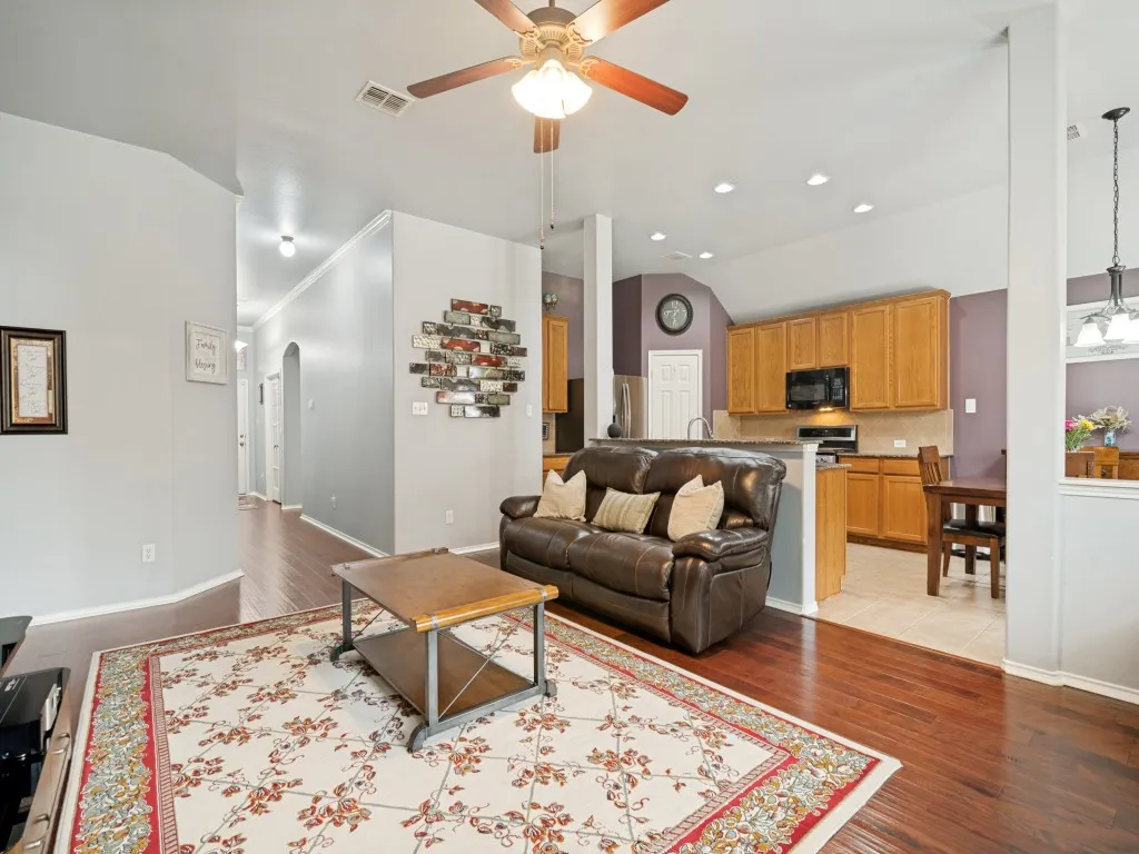 Living room featuring wood-finish flooring, a ceiling fan with integrated lighting, and recessed lighting
