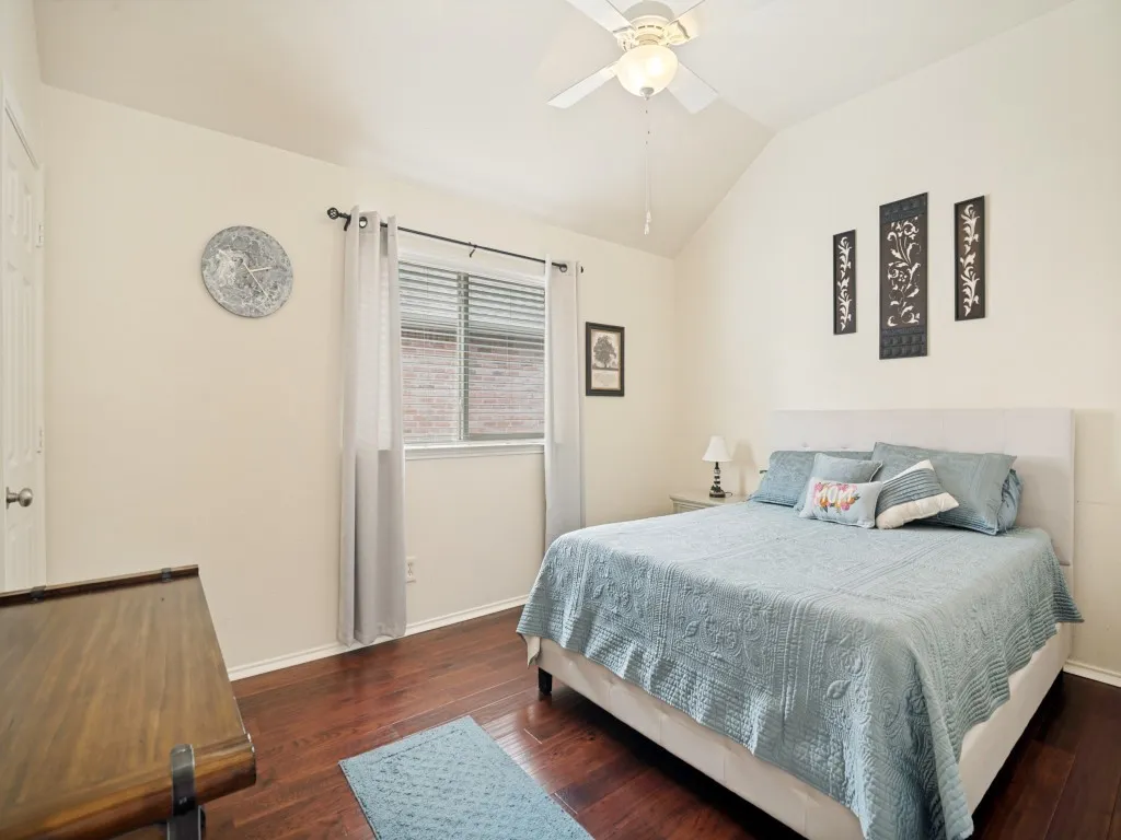Vaulted ceiling bedroom featuring wood-finish flooring, a window with blinds, and a ceiling fan with integrated lighting