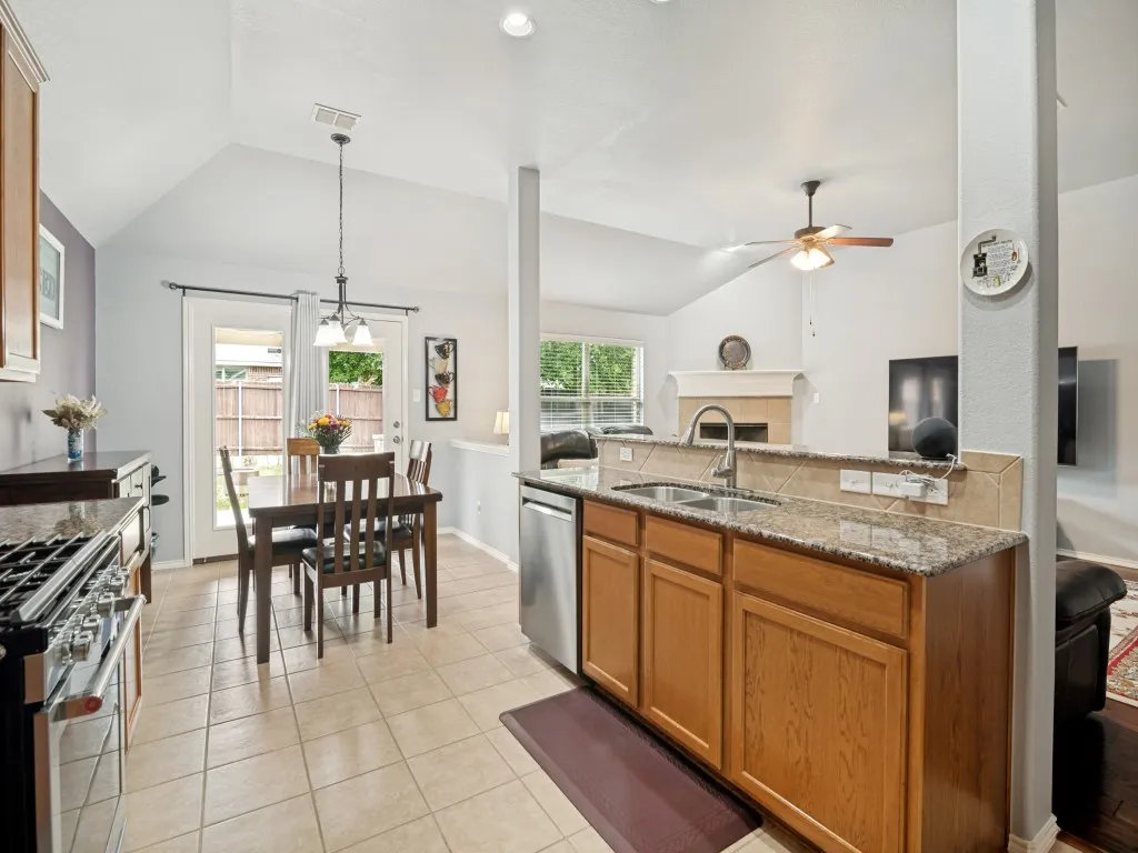 Open-concept kitchen and dining area featuring a breakfast bar with granite-style countertops, tile backsplash, and stainless-steel appliances