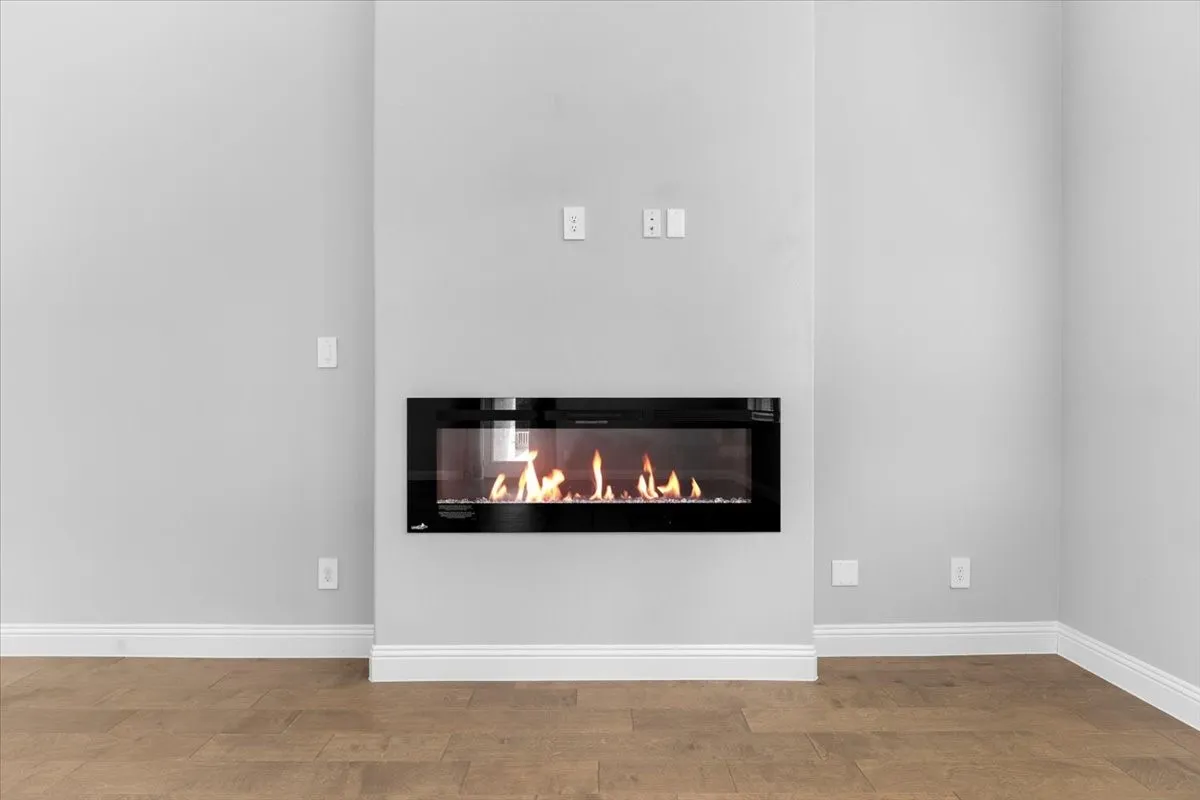 Contemporary electric fireplace with a black glass front, integrated into a light gray wall