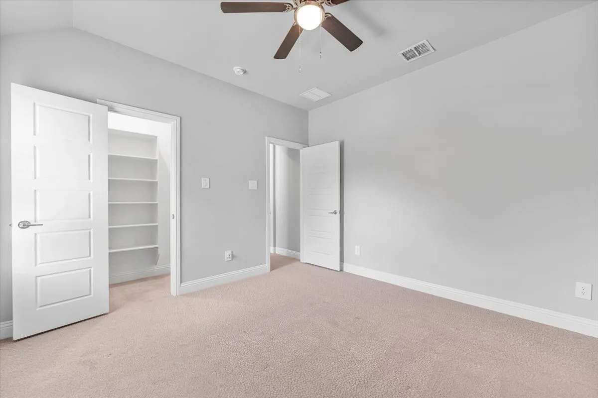 Carpeted room featuring a ceiling fan with integrated lighting, light gray wall paint, and white trim
