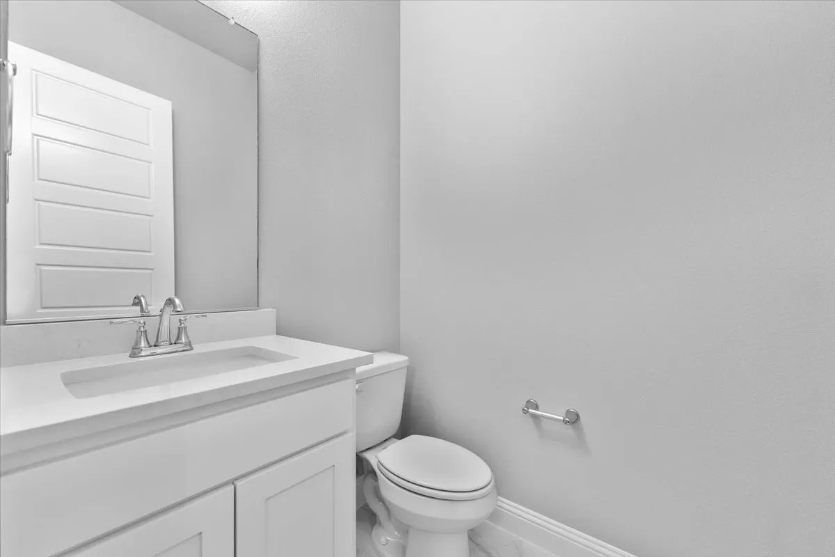 Bathroom featuring a white vanity with an integrated sink, chrome faucet, and a large wall mirror