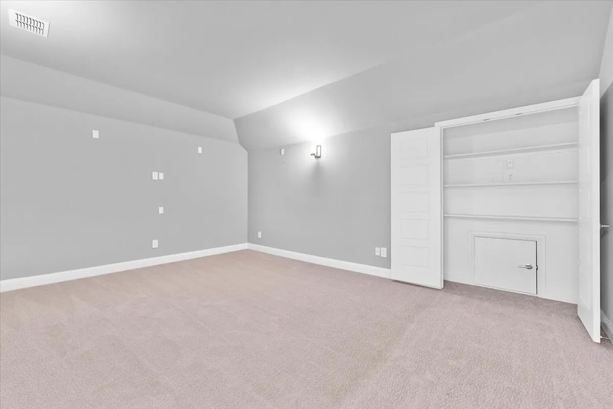 Media room with built-in shelving, white baseboards, wall sconce lighting, and multiple electrical outlets