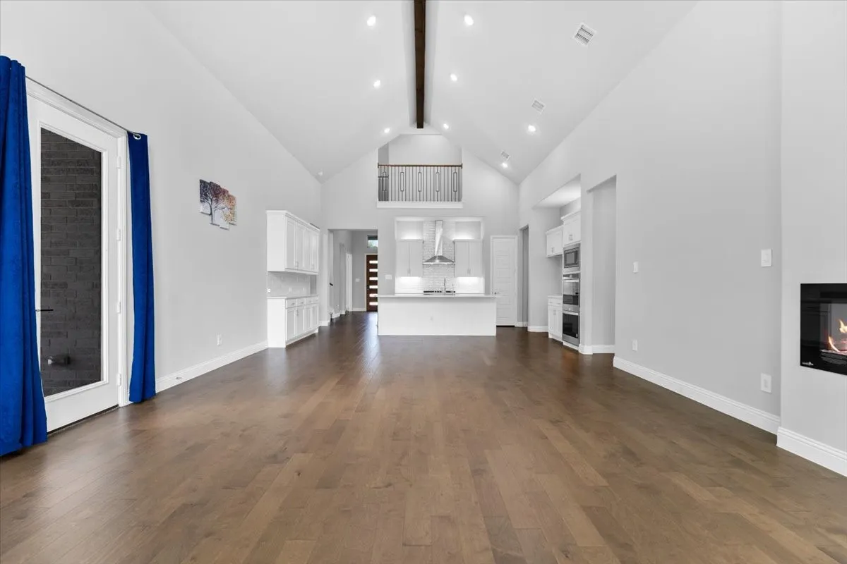 Vaulted ceiling great room featuring wood-finish flooring, recessed lighting, and an integrated fireplace