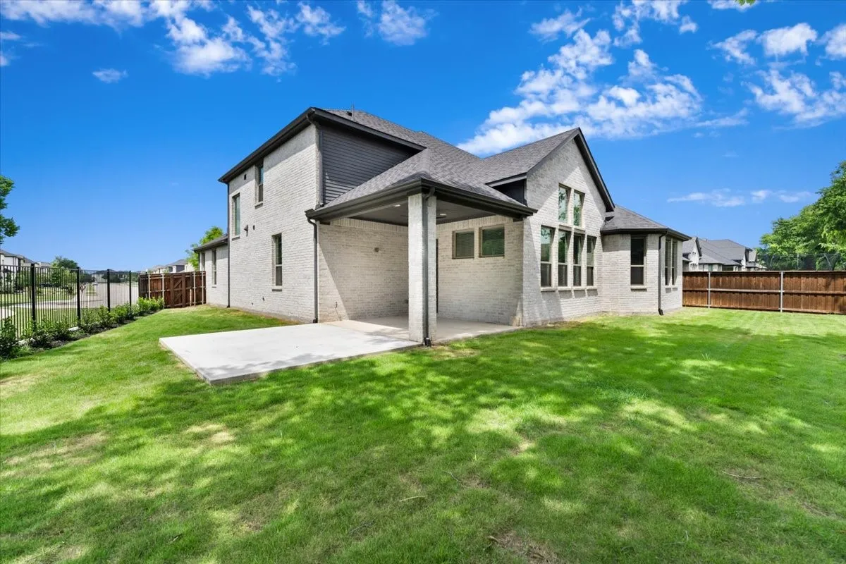 Expansive green lawn with a covered concrete patio