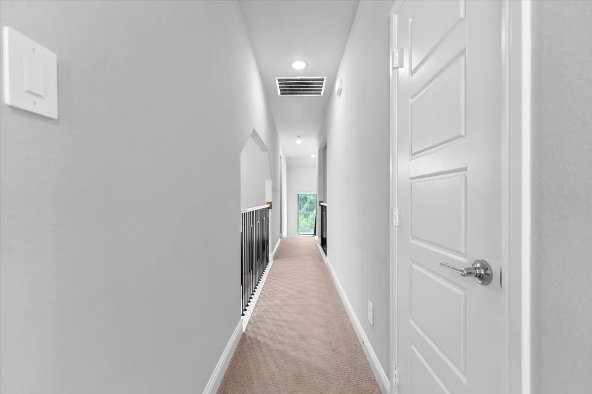 Upper-level hallway with neutral wall paint and light-toned carpet flooring