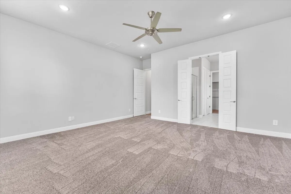 Spacious room featuring neutral carpeting, recessed lighting, and a ceiling fan