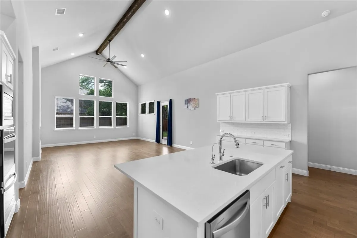 Kitchen island featuring a stainless steel sink, pull-down faucet, and white countertop
