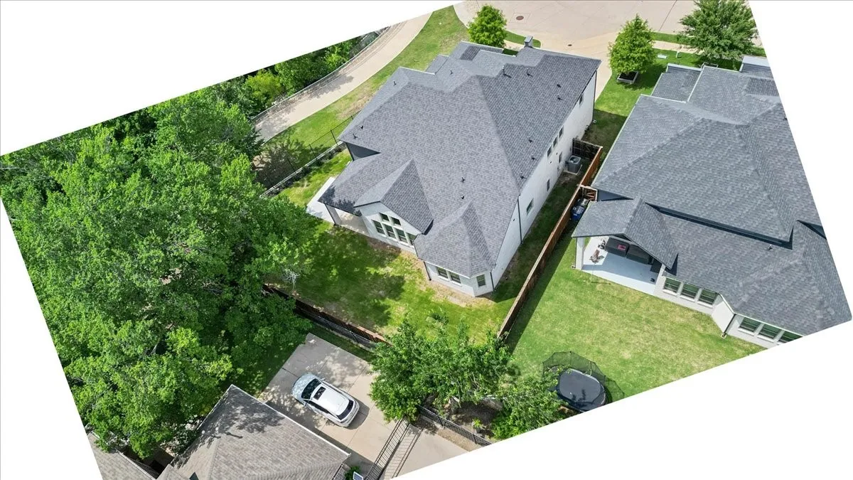 Spacious backyard featuring a manicured lawn, established landscaping, and a concrete patio