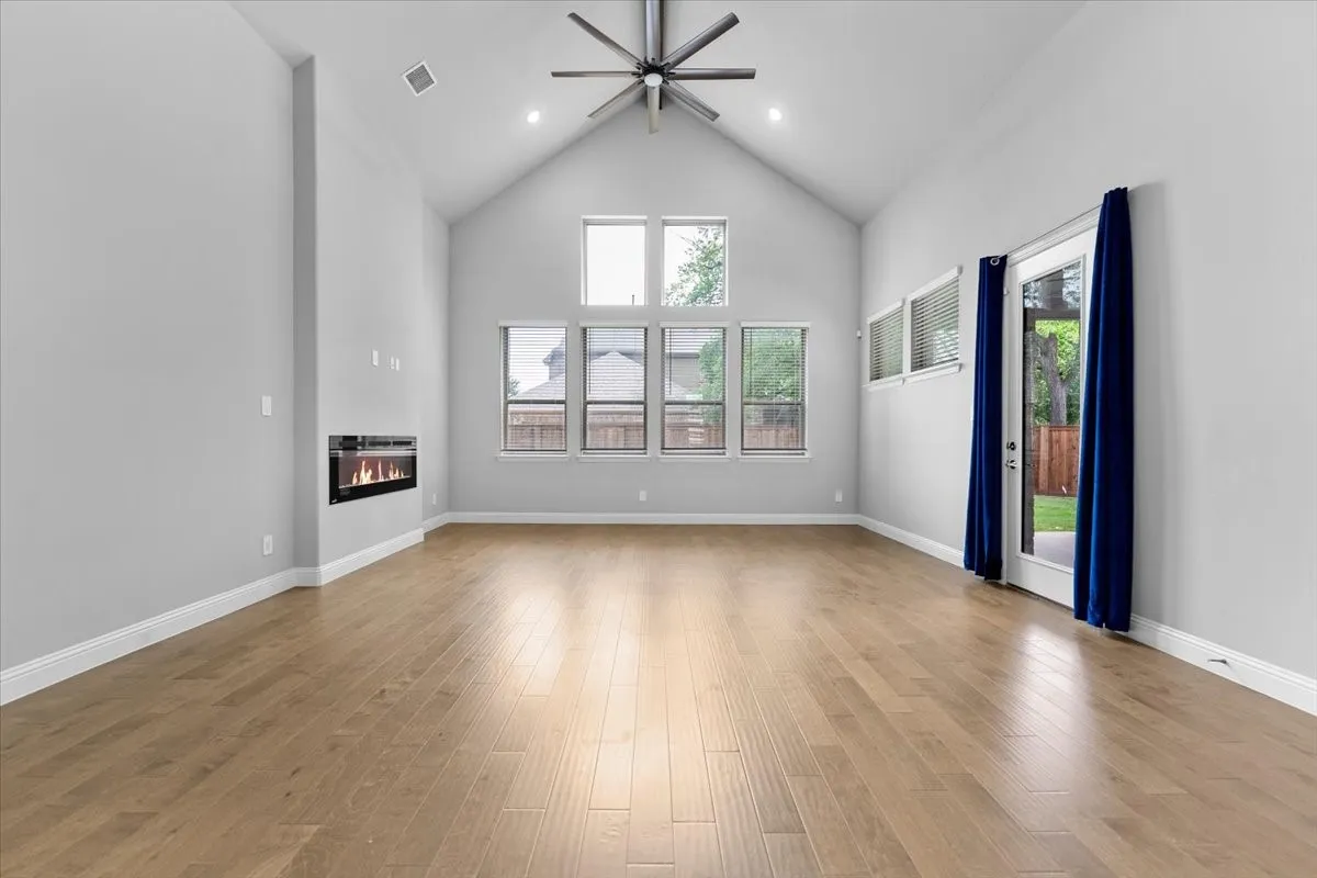 Expansive living area featuring a vaulted ceiling and wood-finish flooring