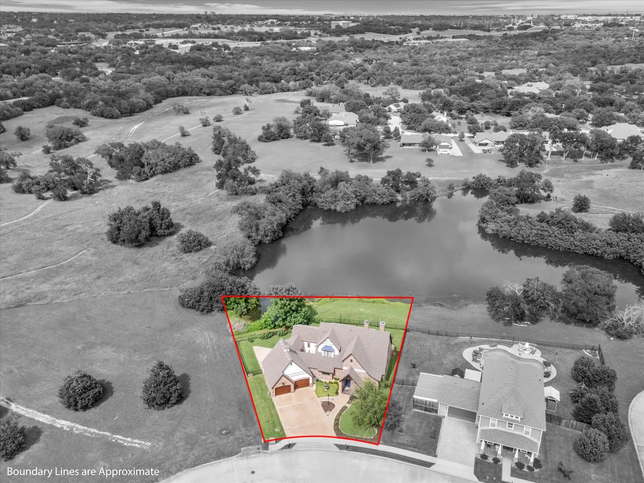 Aerial perspective showcasing a property with a distinct, angular lot bordering a sizable pond