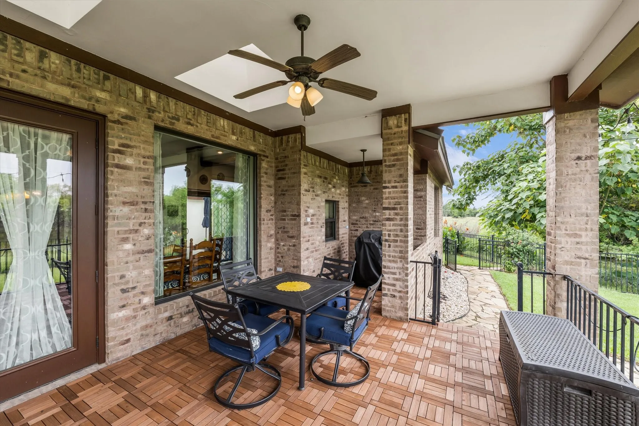 Covered patio with brick columns, wood-finish flooring, a ceiling fan, and access to a fenced backyard