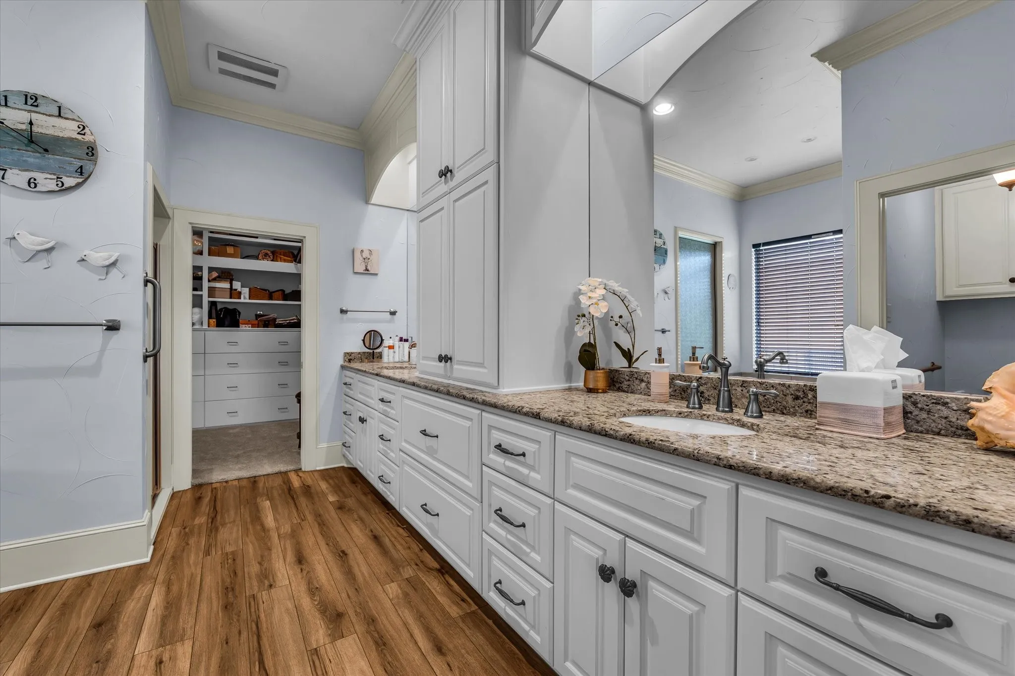 Spacious vanity featuring double sinks, extensive white cabinetry, and granite countertops