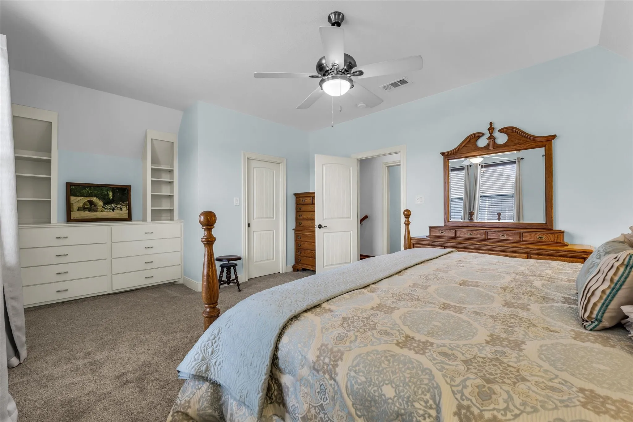 Carpeted room featuring a ceiling fan with integrated lighting, a built-in dresser with shelving, and white paneled doors
