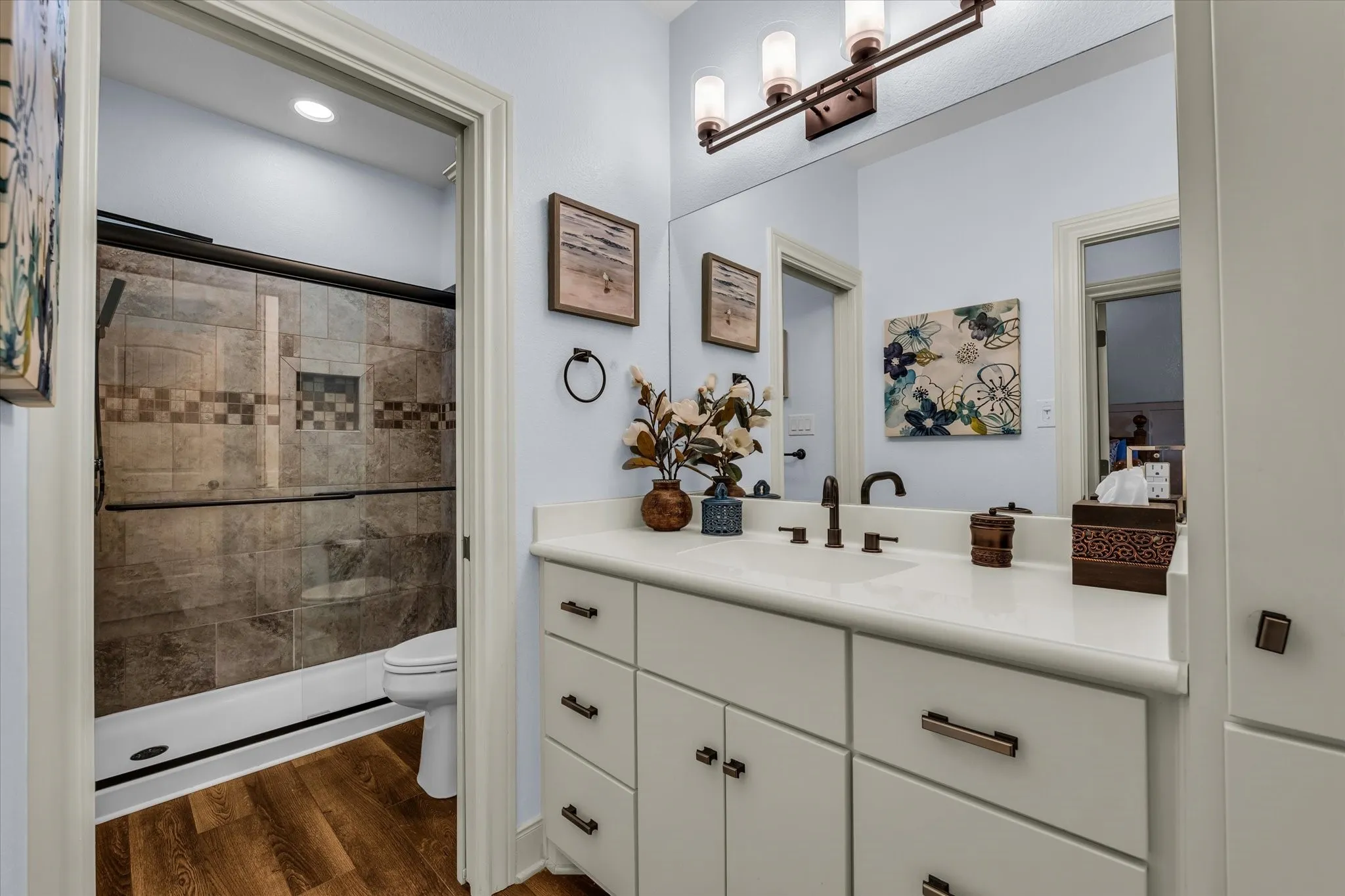 Bathroom featuring a white vanity with integrated sink, bronze fixtures, and a large mirror