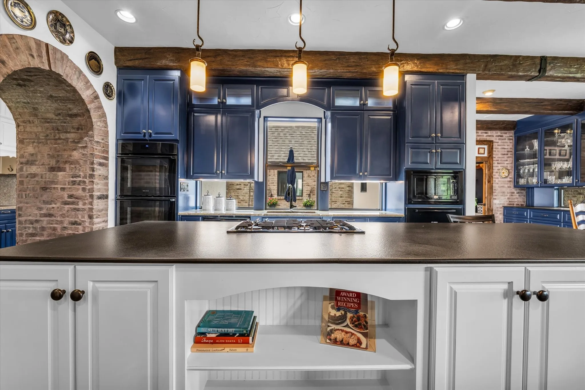 Kitchen featuring a large island with dark countertop, blue cabinetry, and built-in double ovens