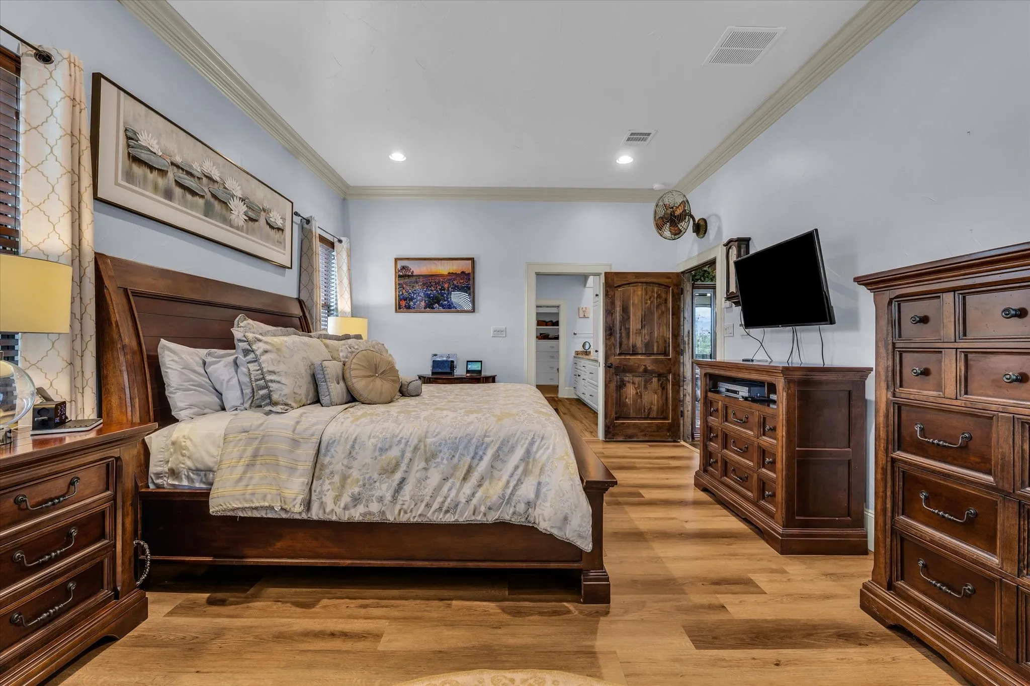 Spacious room with wood-finish flooring, light blue walls, and white crown molding