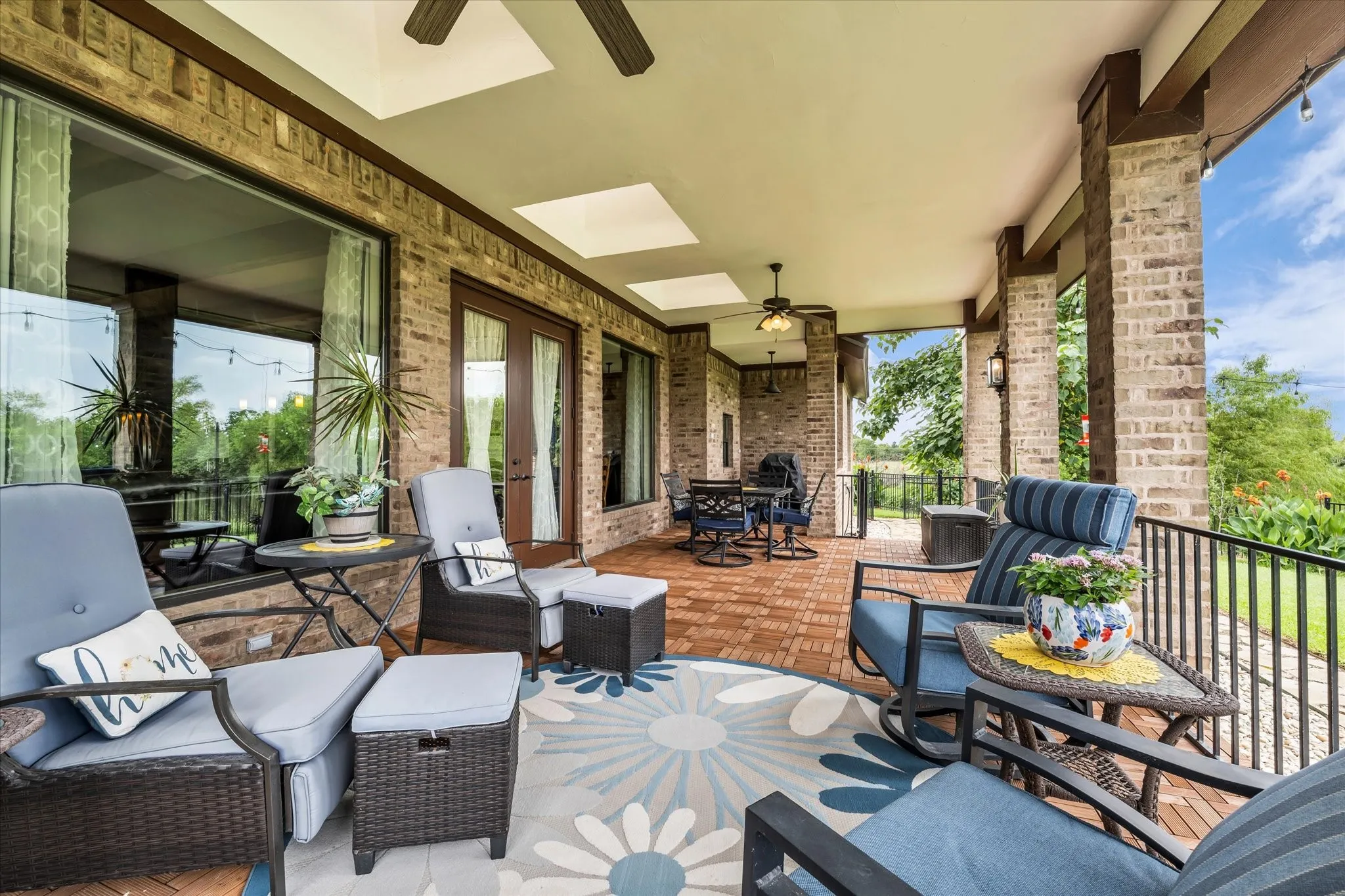 Expansive covered patio featuring brick flooring, ceiling fans, recessed lighting, and brick support columns