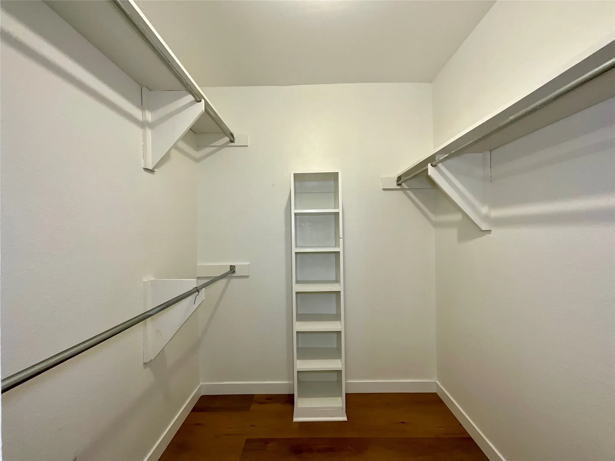 Walk-in closet with wood-finish flooring, white walls, and white baseboards