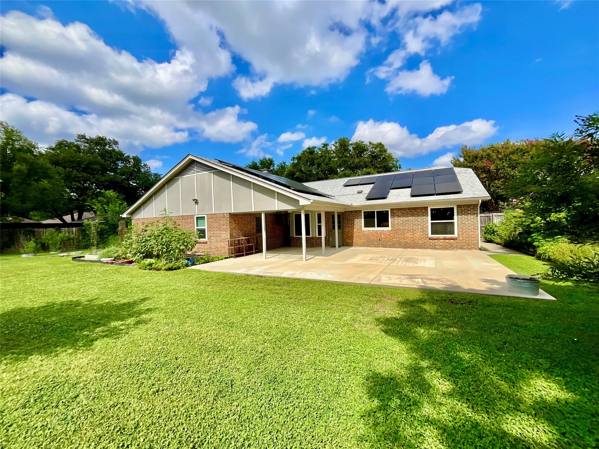 Expansive green lawn with a covered concrete patio