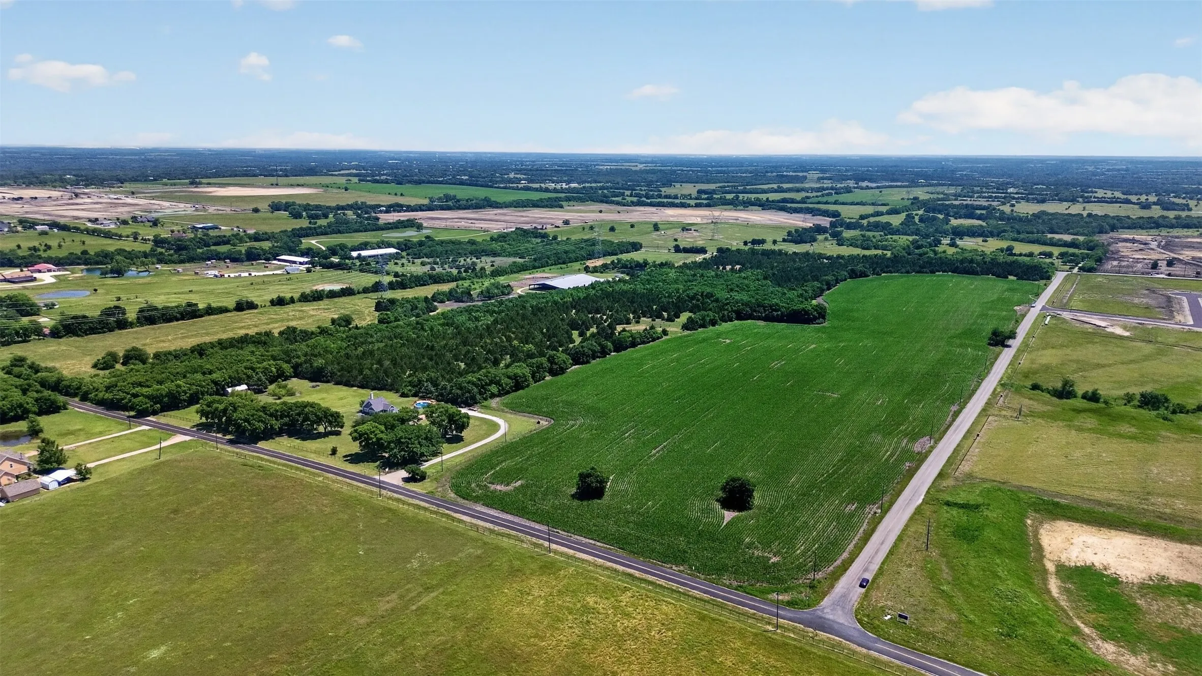 Expansive green fields with surrounding treelines