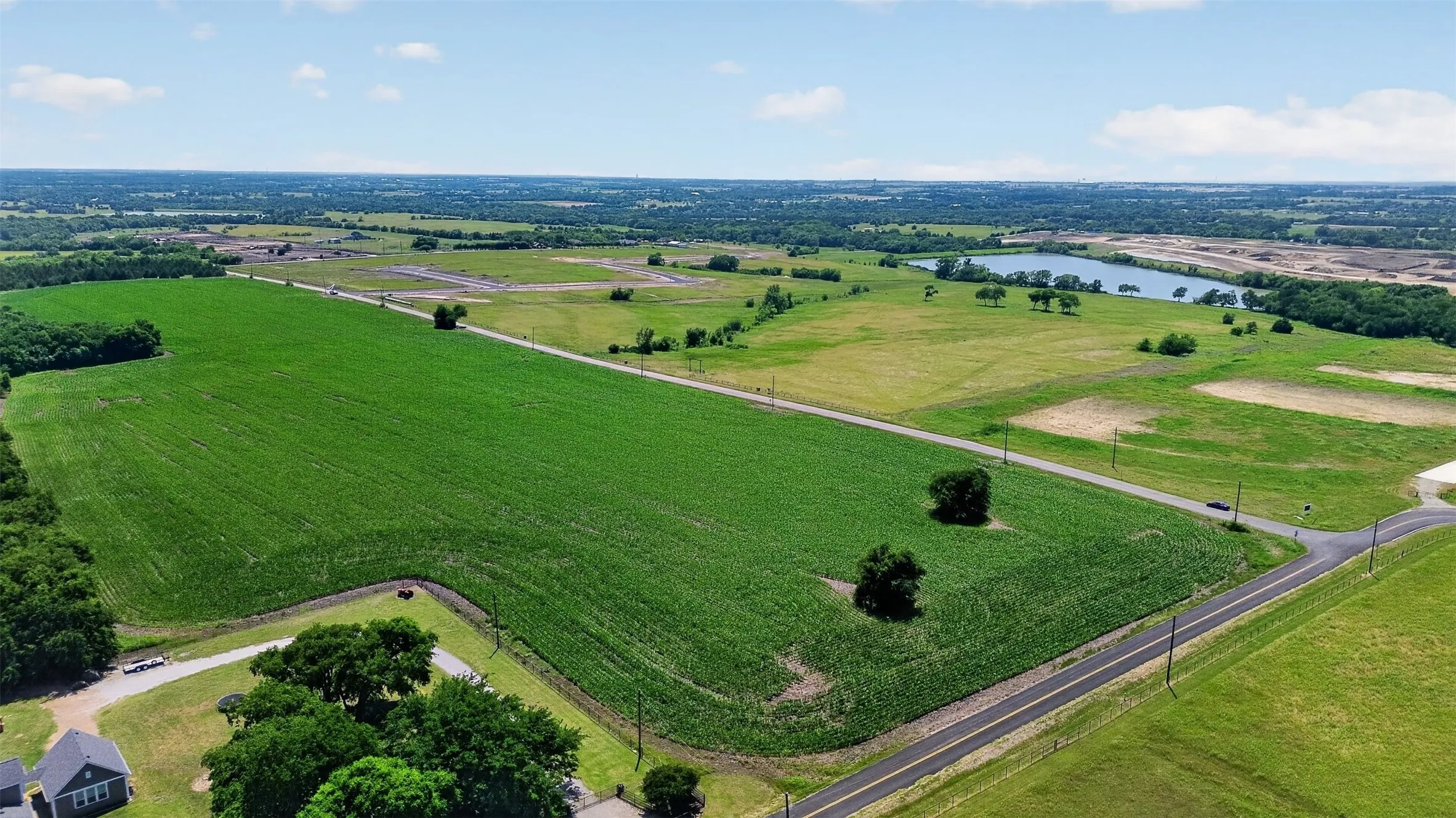 Expansive acreage featuring established roadway access, an open field, and mature tree clusters