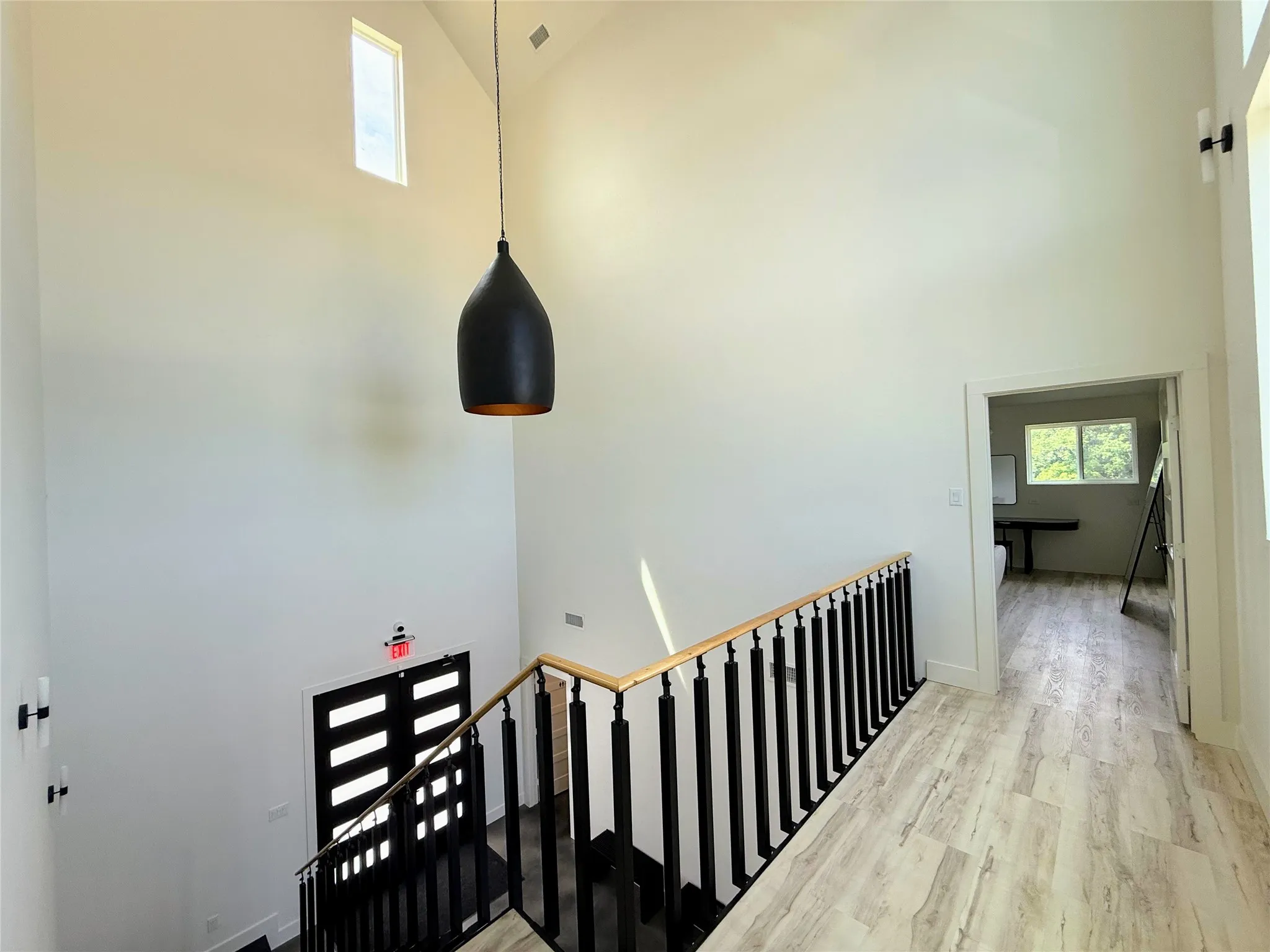 Two-story entryway featuring a vaulted ceiling and a black pendant light fixture