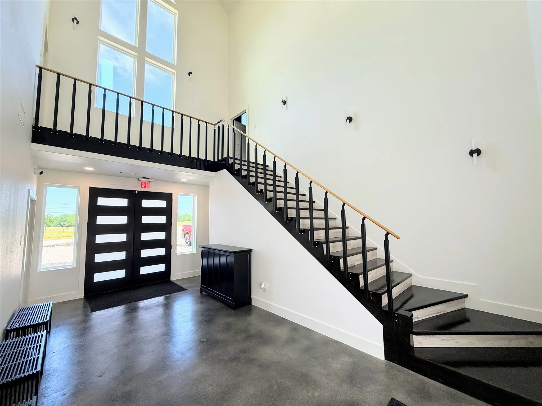 Two-story entryway featuring a prominent staircase with black metal balusters and a light wood-finish handrail