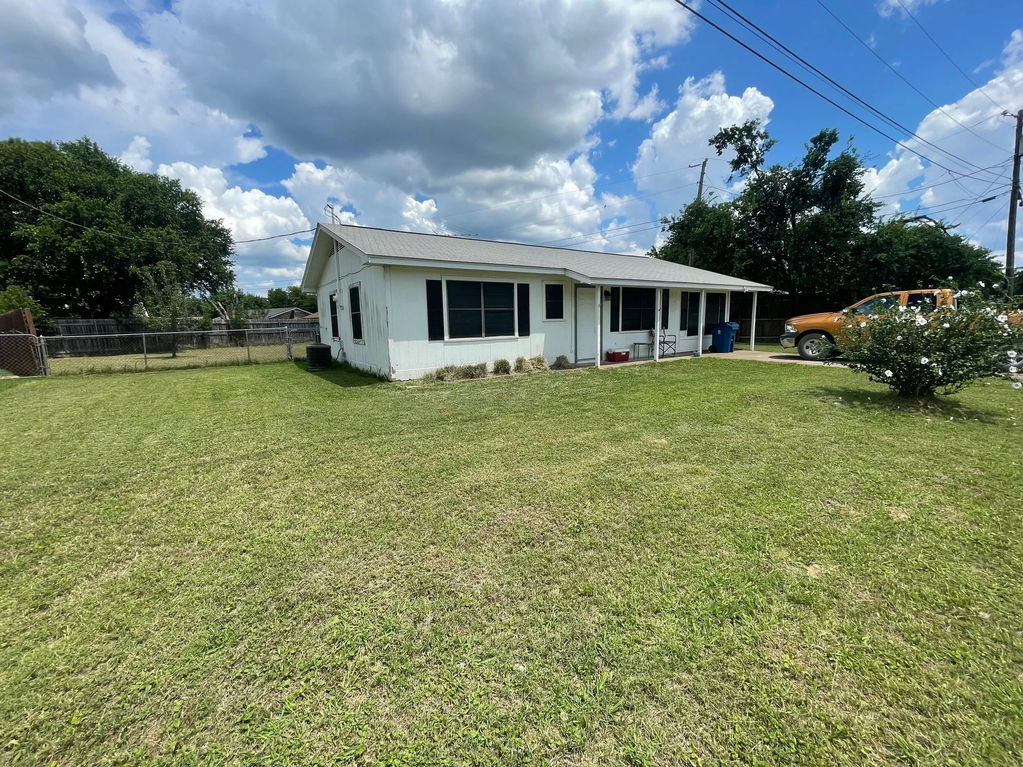 Left side of property, featuring front lawn, fence and partial backyard