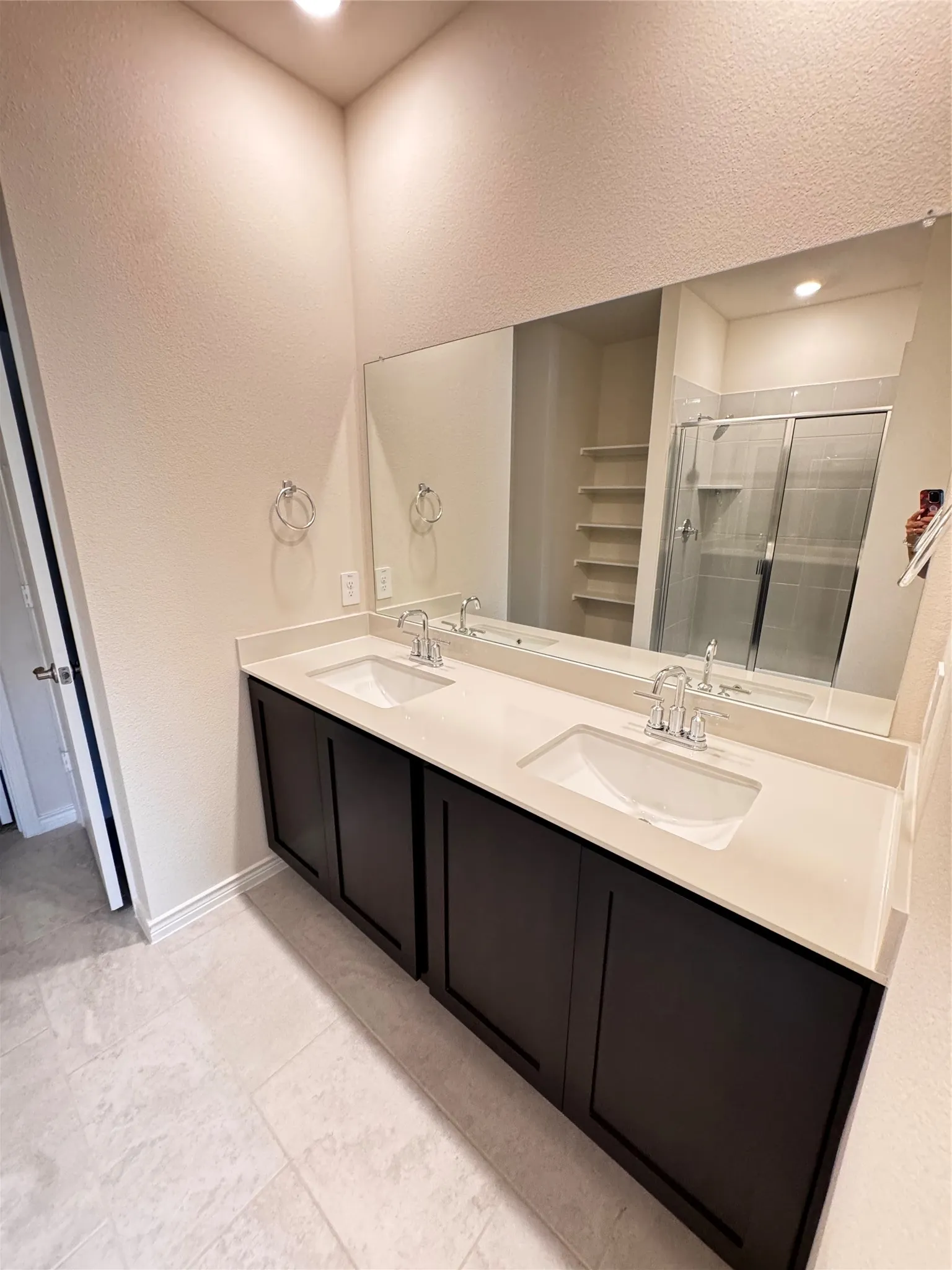 Double vanity featuring dark wood-finish cabinetry, integrated sinks, and a light-toned countertop